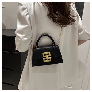 Détail d'un sac bandoulière en cuir noir avec serrure dorée et bandoulière en chaîne