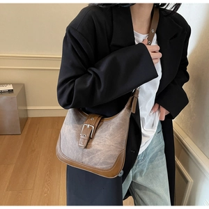 Sac bandoulière réglable en cuir et toile porté par un mannequin dans un intérieur chic