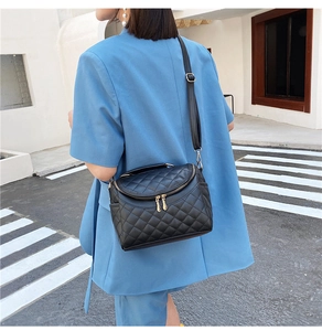 Detail of black quilted PU leather handbag with golden dual zippers and top handle