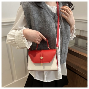 Detail of red and cream leather handbag featuring a round golden metallic lock buckle