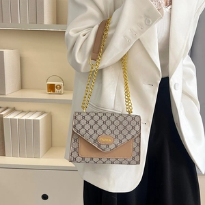 Sac bandoulière rétro monogramme avec chaîne dorée présenté dans un intérieur moderne