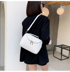 Detail view of white quilted PU leather handbag with gold zippers and a top handle