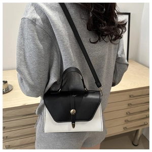 Detail shot of a black and white contrast leather handbag with adjustable crossbody strap