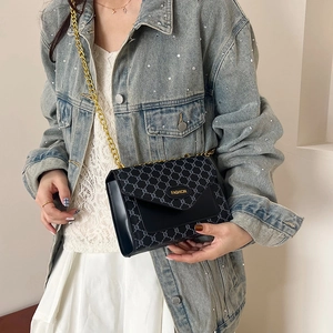 Sac bandoulière vintage noir avec motif géométrique et chaîne dorée porté par mannequin