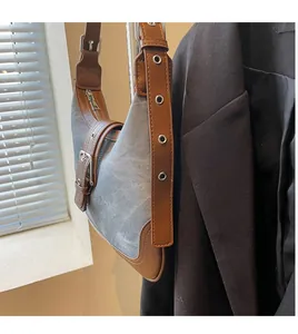 Détail du sac bandoulière vintage en denim gris avec bordures en cuir et œillets métal