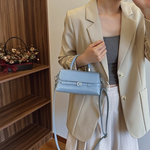Light blue faux leather handbag with metal buckle strap shown in a lifestyle setting