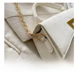 Détail du fermoir doré et de la bandoulière chaîne sur sac en cuir texturé blanc