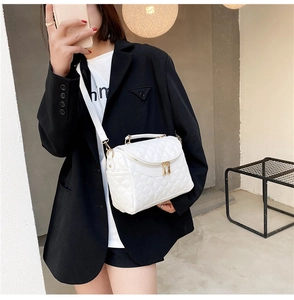 Detailed view of a white quilted PU leather handbag with gold zippers and adjustable strap
