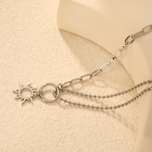 Detail of silver stainless steel sun pendant necklace with industrial double layered chains