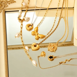Parure de colliers avec papillon et perle baroque sur un miroir vintage doré