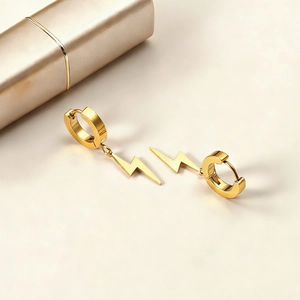 Gros plan de boucles d'oreilles éclair en or poli sur un fond beige doux et chic
