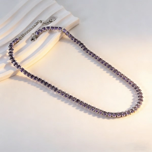 Detailed macro of a purple crystal tennis necklace with silver lobster clasp and extension chain