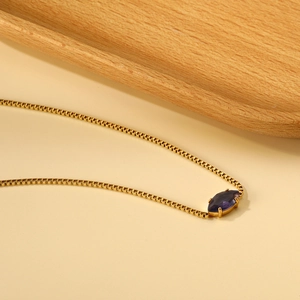 Dettaglio di una collana a catena box dorata con pendente in gemma viola marquise