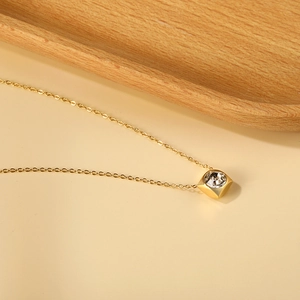 Detail of 18K gold-plated necklace with a square cubic zirconia pendant on a fine cross chain