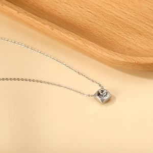 Detail of a square silver pendant with a clear crystal on a minimalist chain necklace