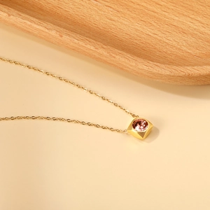 Detail of 18K gold-plated necklace featuring a square pendant with a pink gemstone inlay