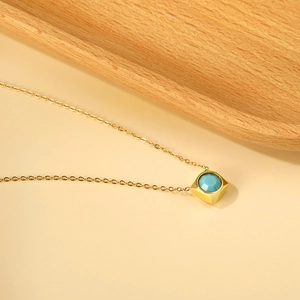 Close-up of a 18K gold plated square necklace with a faceted light blue turquoise stone