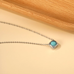 Macro detail of square silver pendant with turquoise stone on classic O-chain necklace