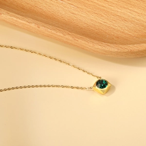 Detail of square gold pendant with faceted green gemstone on a thin 18K gold plated chain