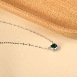 Macro shot of silver square pendant with green gemstone and fine O-link chain