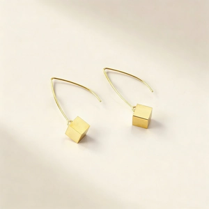 Detailed close-up of golden minimalist V-hook earrings with polished solid cubes