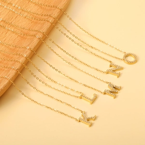 Close-up of gold plated 18K necklaces with sparkling crystal paved letter pendants