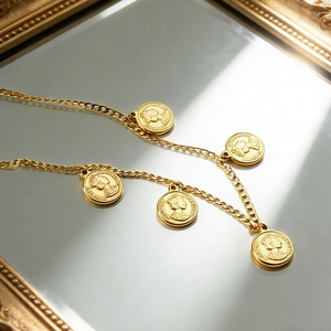 Close-up of five gold-plated coin pendants with portrait engraving on a curb chain