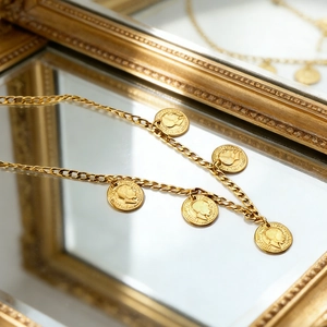 Detailed close-up of gold-plated coin necklace featuring portrait pendants on a mirror