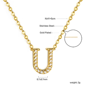 Macro detail of 18K gold plated stainless steel U-letter pendant with sparkling crystals