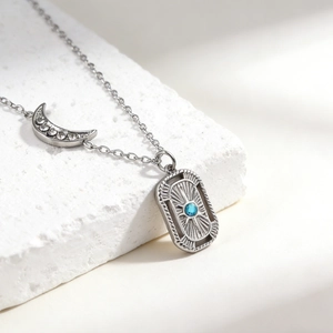 Detail of silver moon pendant with crystals and blue stone rectangular charm necklace