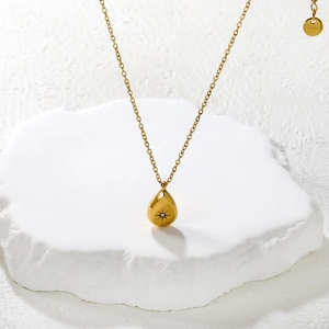 Gold stainless steel teardrop necklace with starburst zircon on a stone pedestal
