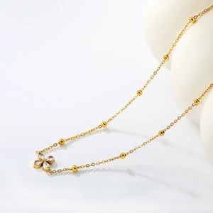 Close-up of gold chain necklace with flower pendant and white zircons on white artistic props