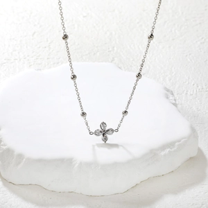 French style stainless steel necklace featuring a white zircon petal pendant on a stone stand