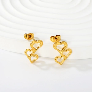 Boucles d'oreilles pendantes cœurs évidés en acier doré sur socle blanc
