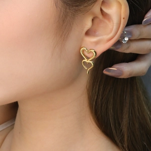 Boucles d'oreilles cœurs évidés entrelacés dorés portées par un mannequin en gros plan