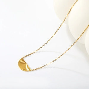 Collier à pendentif demi-cercle doré avec texture radiale sur fond blanc minimaliste