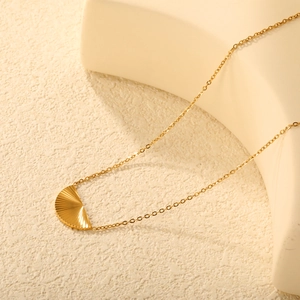 Collier avec pendentif demi-cercle doré et texture soleil sur fond élégant raffiné