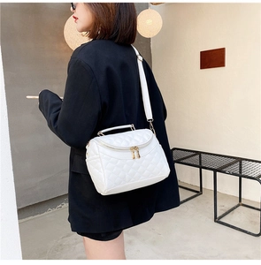 Detail of white quilted PU leather handbag featuring dual zippers and a wide shoulder strap