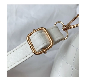 Detail of adjustable strap with gold-tone hardware on white quilted cosmetic bag