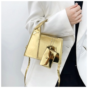 Sac à main carré doré brillant avec mini breloque et bandoulière porté par un mannequin chic