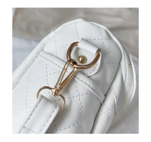 Detail of white quilted PU leather handbag featuring light gold metal buckle and D-ring
