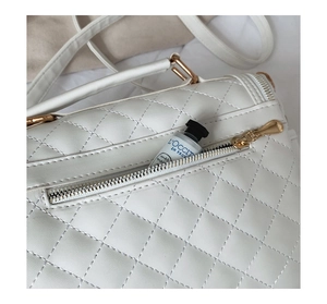 Detail of white quilted handbag with a gold-tone zipper back pocket and cream lining