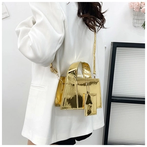 Détail du sac à main doré brillant avec mini pochette sur une veste de blazer blanche