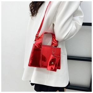 Détail du sac à main rouge en cuir brillant avec mini pochette et bouton pression doré