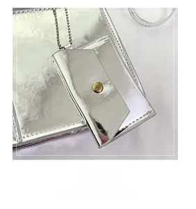 Gros plan du porte-monnaie argenté effet miroir avec texture froissée et bouton bronze