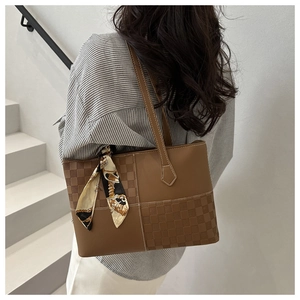 Detail of brown tote bag with checkered texture and silk scarf on modern stairs