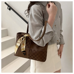 Detail of dark brown checkered tote bag with decorative silk scarf on model