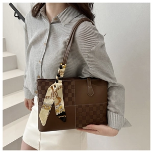 Detail of brown checkered tote bag with decorative silk scarf on minimalist staircase