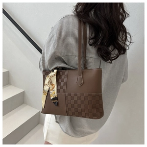 Detail of checkered patchwork tote bag with silk scarf on a model for a retro look