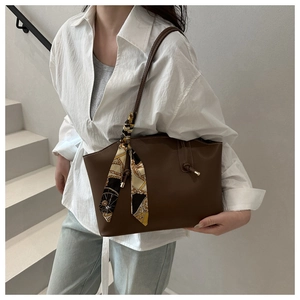 Detail of dark brown tote bag featuring decorative patterned scarf and knotted shoulder strap